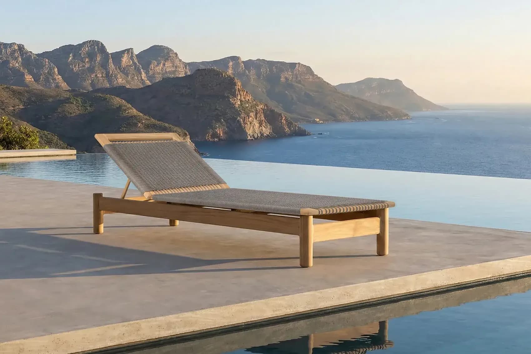 Teak sun lounger on a pool deck facing the sea