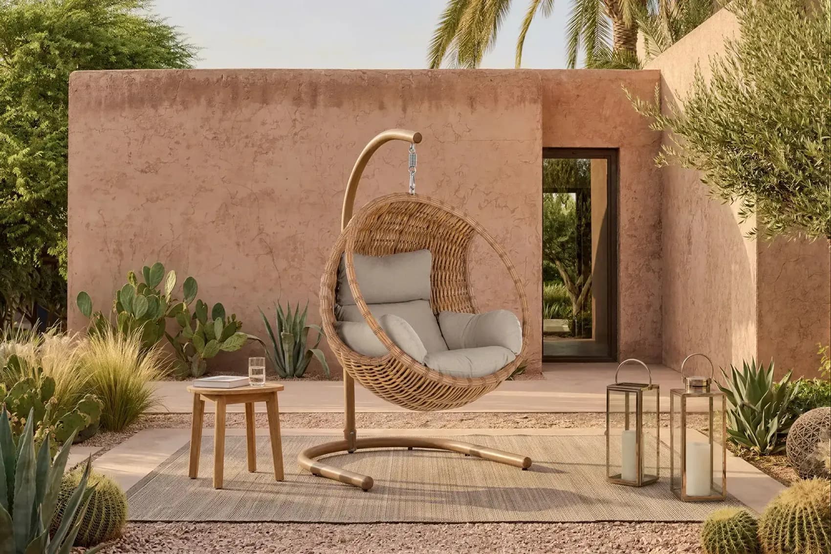 Woven egg shaped swing chair on a steel stand in a courtyard