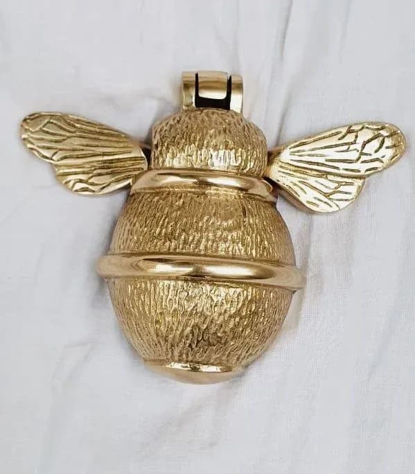Gold finish brass bee door knocker on white cloth